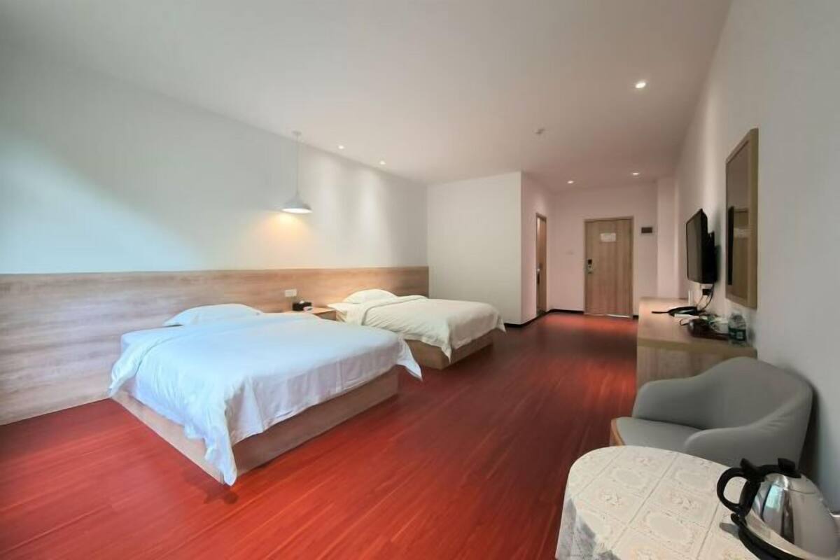 Une chambre d’hôtel avec deux lits, une tête de lit en bois, un téléviseur à écran plat, une machine à café et une chaise.