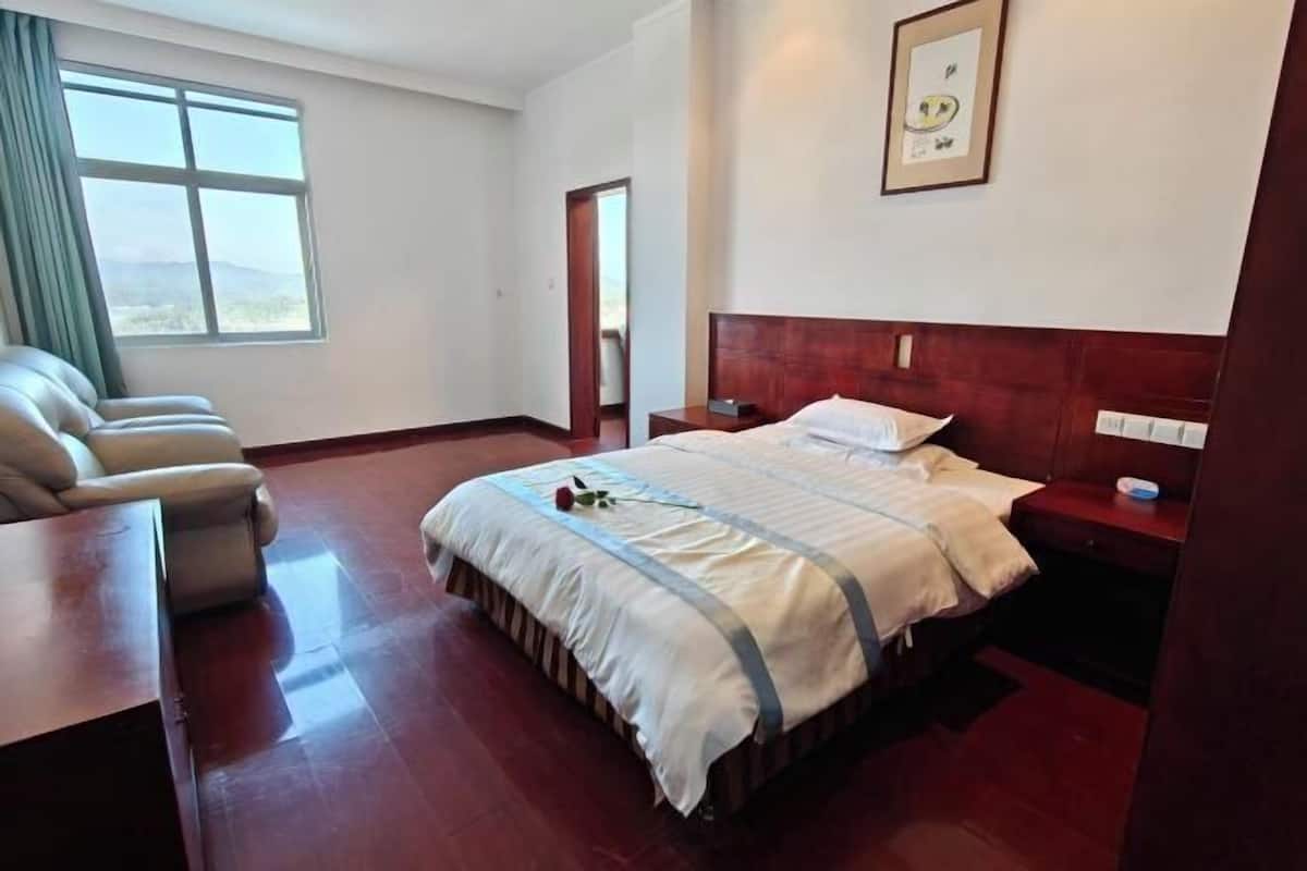 Une chambre d’hôtel avec un grand lit, un bureau, une chaise et une fenêtre donnant sur un beau paysage.