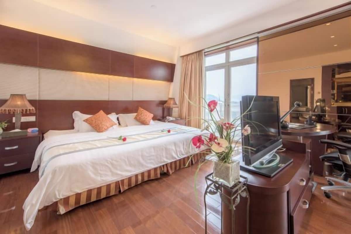 Une chambre d’hôtel avec un grand lit, un bureau avec un ordinateur et une grande fenêtre.