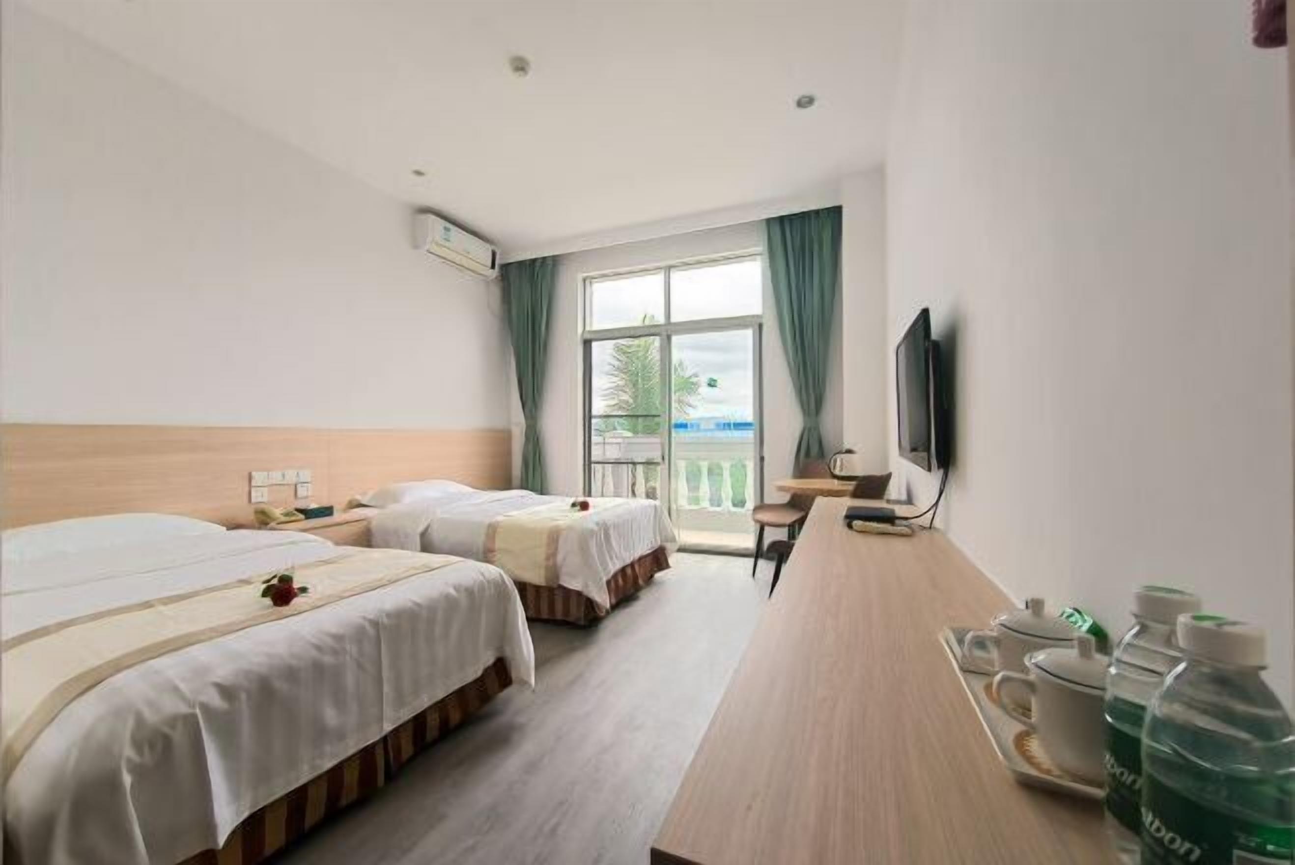 Ein Hotelzimmer mit zwei Betten, einem Schreibtisch, einem Fernseher und einem Balkon mit Blick.