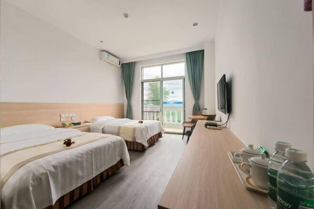 Une chambre d’hôtel avec deux lits, un bureau, une télévision et un balcon avec vue.