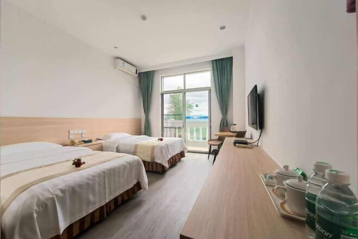 Une chambre d’hôtel avec deux lits, un bureau, une télévision et un balcon avec vue.