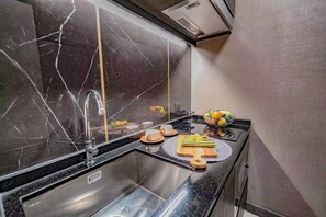 Una cocina moderna con salpicadero de mármol, electrodomésticos de acero inoxidable y una zona de desayuno con huevos, fruta y café.