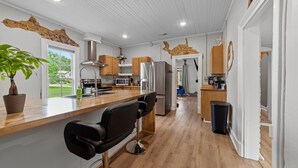 A modern kitchen with wooden countertops, stainless steel appliances, and black bar stools.