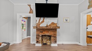 A living room with a brick fireplace, a mounted TV, and a wooden coffee table.