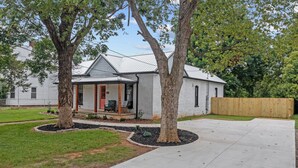 A single-story house with a front porch, a covered entryway, and a fenced backyard.