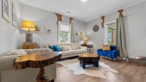 A living room with a sofa, a blue armchair, a wooden coffee table, and a rug.