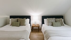 Et to-person værelse med to senge, et natbord og en lampe.