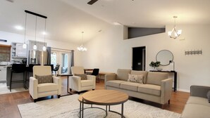 Un salon moderne comprenant un canapé, des fauteuils, une table basse et un coin repas avec une table et des chaises.