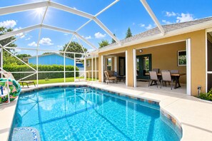 Une piscine avec un patio couvert, des espaces de détente en plein air et une vue sur le paysage environnant.