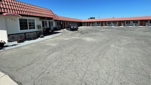 A motel with a red-tiled roof, numbered rooms, and a parking lot. - Travel Inn (Greenfield)