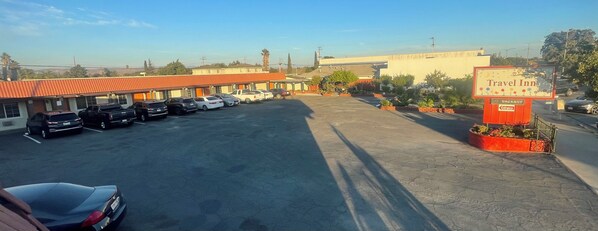 A Travel Inn with a parking lot filled with cars, a sign indicating no parking, and a clear sky.