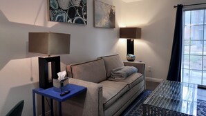 A modern living room with a sofa, two wall-mounted lamps, and abstract art. - Comfortable 1 bdrm with a office Nook (Las Vegas)
