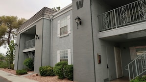 A two-story residential building with a grey facade, white shutters, and a balcony with decorative metal railings. - Comfortable 1 bdrm with a office Nook (Las Vegas)