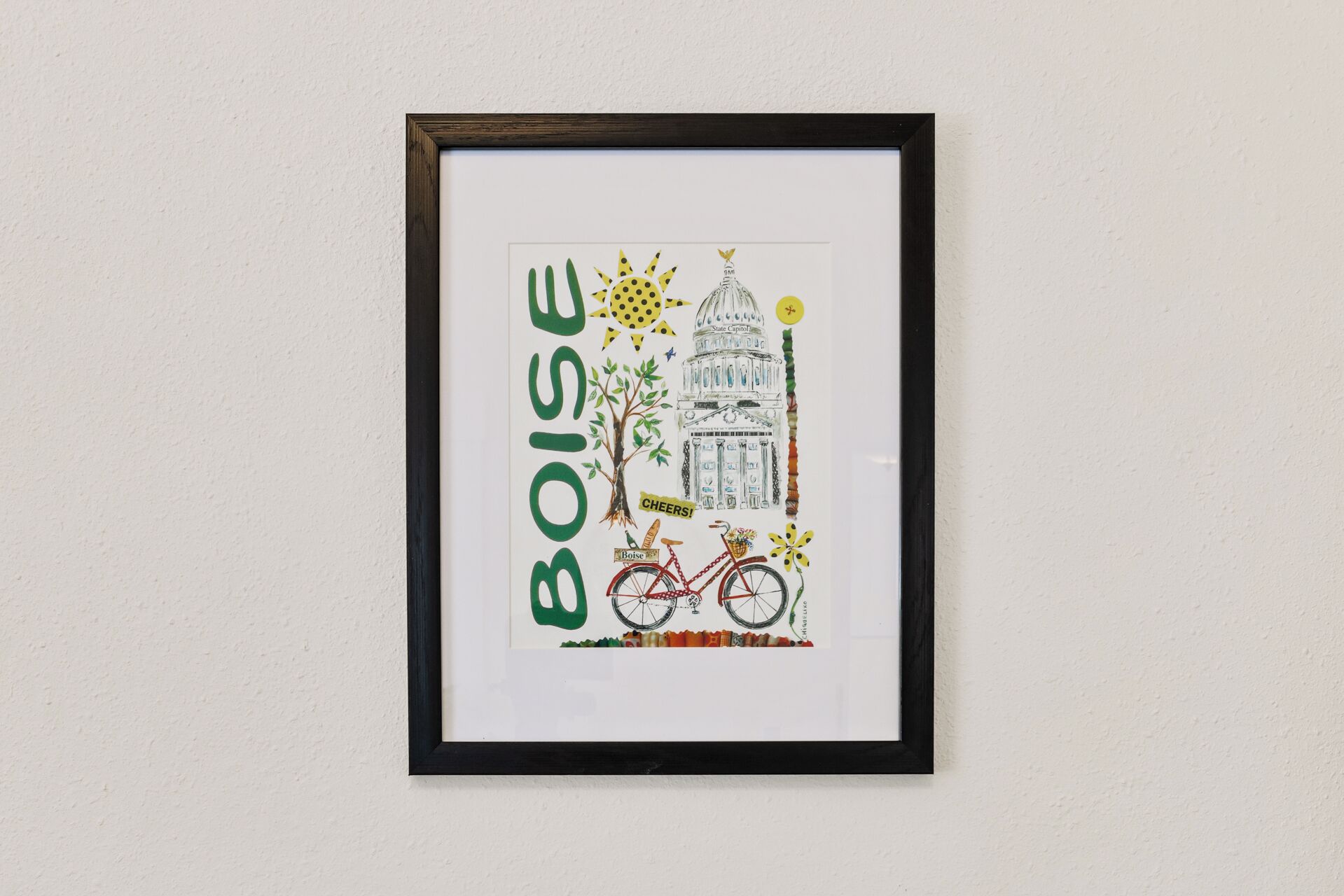 Een lijst met een tekening van het Capitool van Boise, een fiets en een boom.