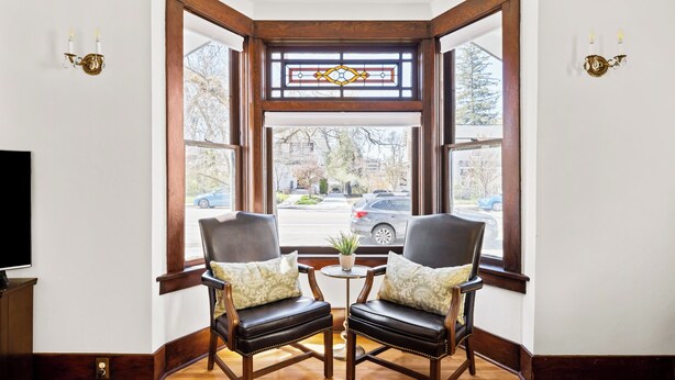 Een hoekzaal met twee leren fauteuils, een bijzettafeltje en uitzicht door een glas-in-loodraam.