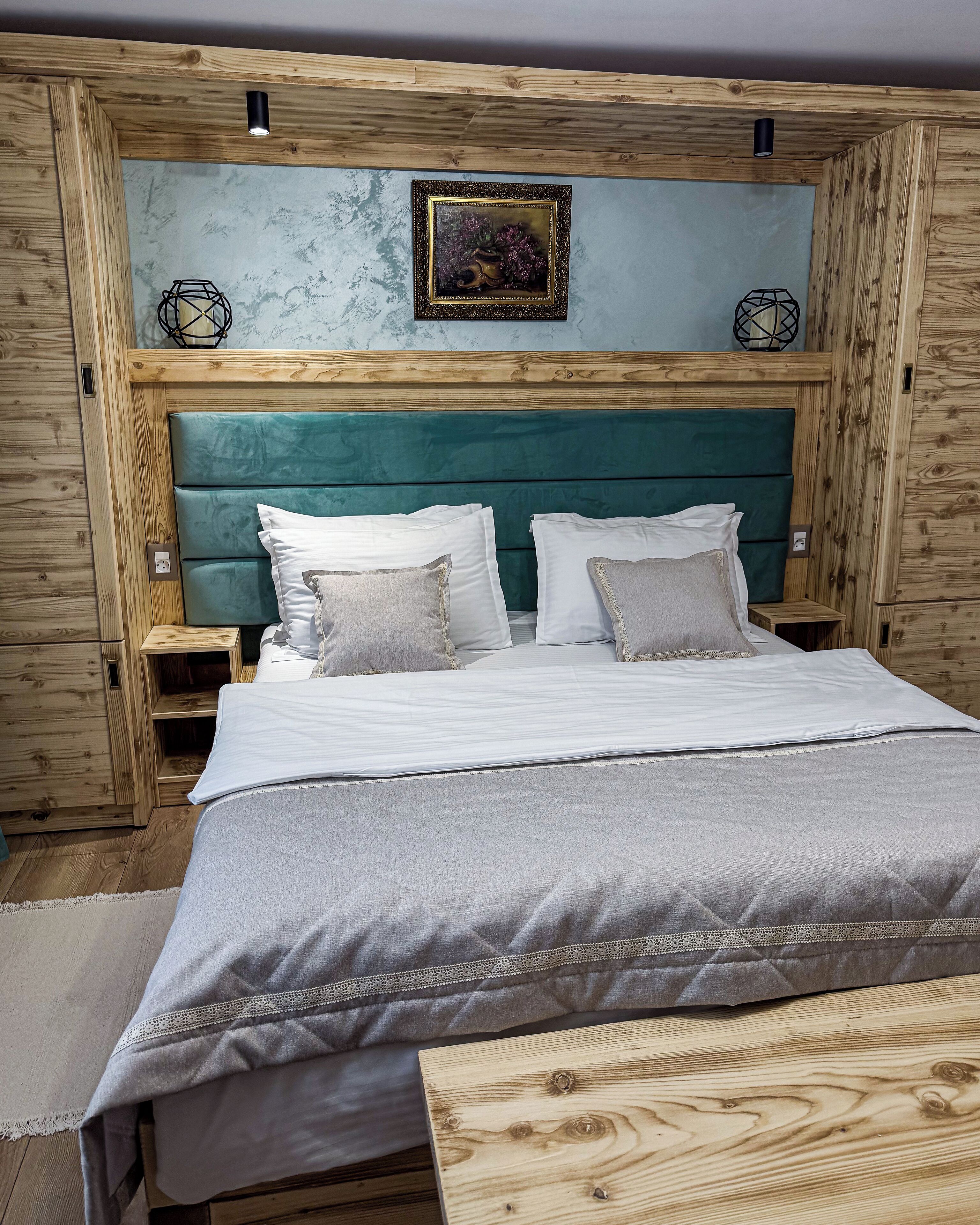A wooden-paneled bedroom with a teal headboard, white bedding, and two bedside tables.