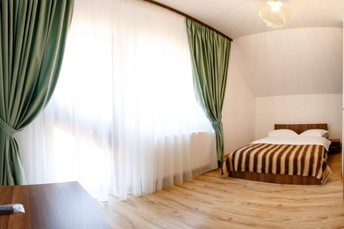 Une chambre d’hôtel avec un lit, un bureau en bois et une télécommande posée sur le bureau.