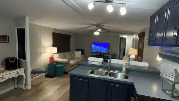 A modern kitchen with a central island, a dining area with a sofa, and a TV in the background. - Let Freedom Ring! (Hampstead)