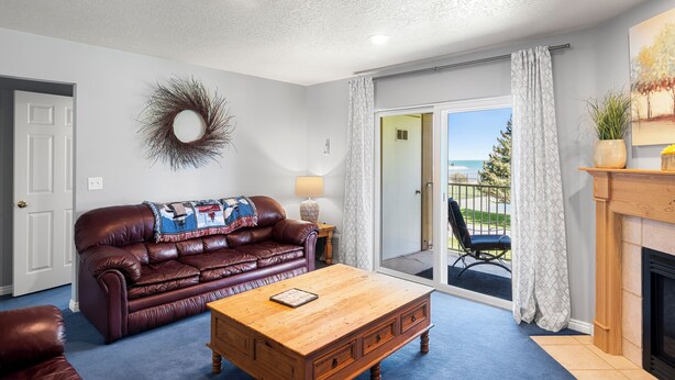 A living room with a leather sofa, a wooden coffee table, and a fireplace. - Condo - #310 | 2 Bed, 2 Bath (Garden City)