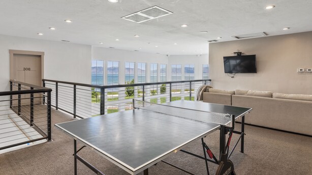 Ett rymligt rum med ett bordtennisbord, en soffa och en tv som hänger på väggen.