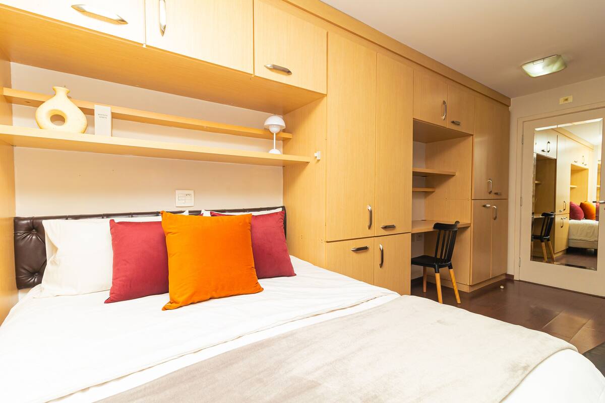 Une chambre à coucher avec un lit, une chaise et des armoires en bois.