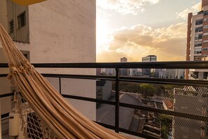 Een hangmat op een balkon met uitzicht op de stad.