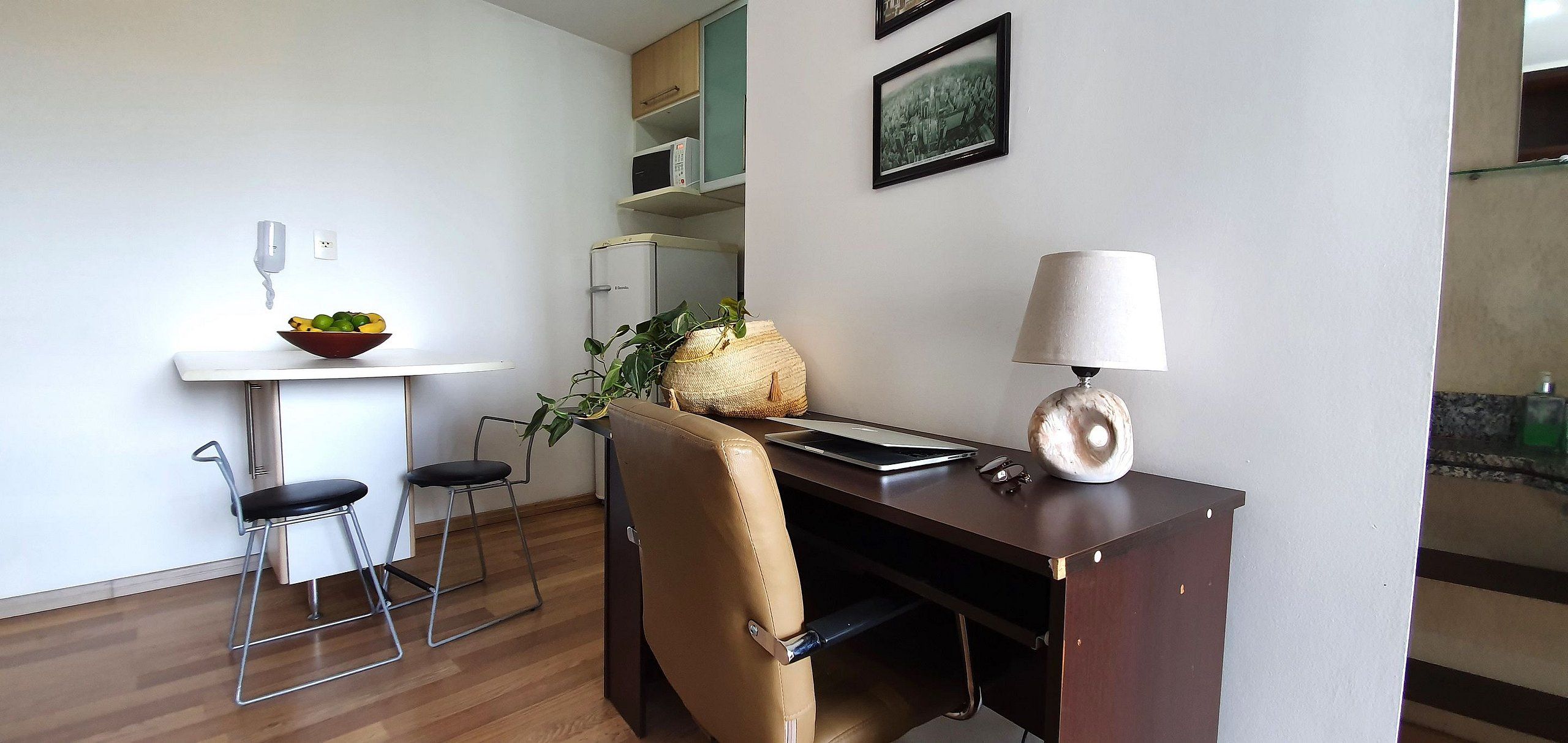 A compact living space with a kitchenette, a dining area, and a desk with a laptop.