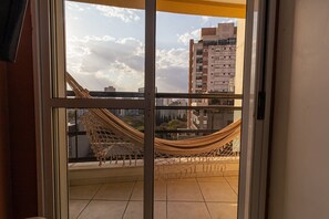 Un balcón con una hamaca y vistas a un paisaje urbano.