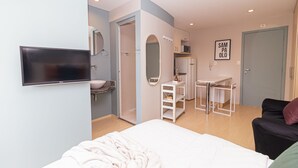 A modern hotel room with a bed, a TV, a bathroom with a sink and mirror, and a door with a sign. - Vossa Bossa Bela Cintra Home (São Paulo)