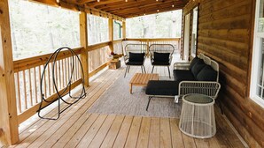 Une terrasse en bois avec un canapé, des chaises et un fauteuil suspendu.