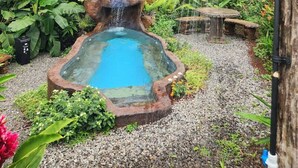 Un jardin aménagé dans un style naturaliste, agrémenté d’une cascade artificielle en roches, d’un petit étang et d’un espace de détente.
