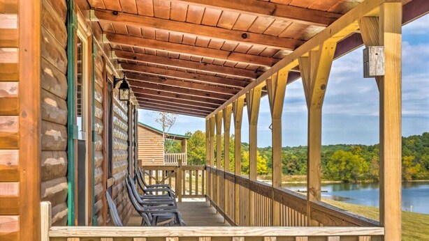 Un espace extérieur abrité, doté de bancs, de rampes en bois et offrant une vue sur un lac.
