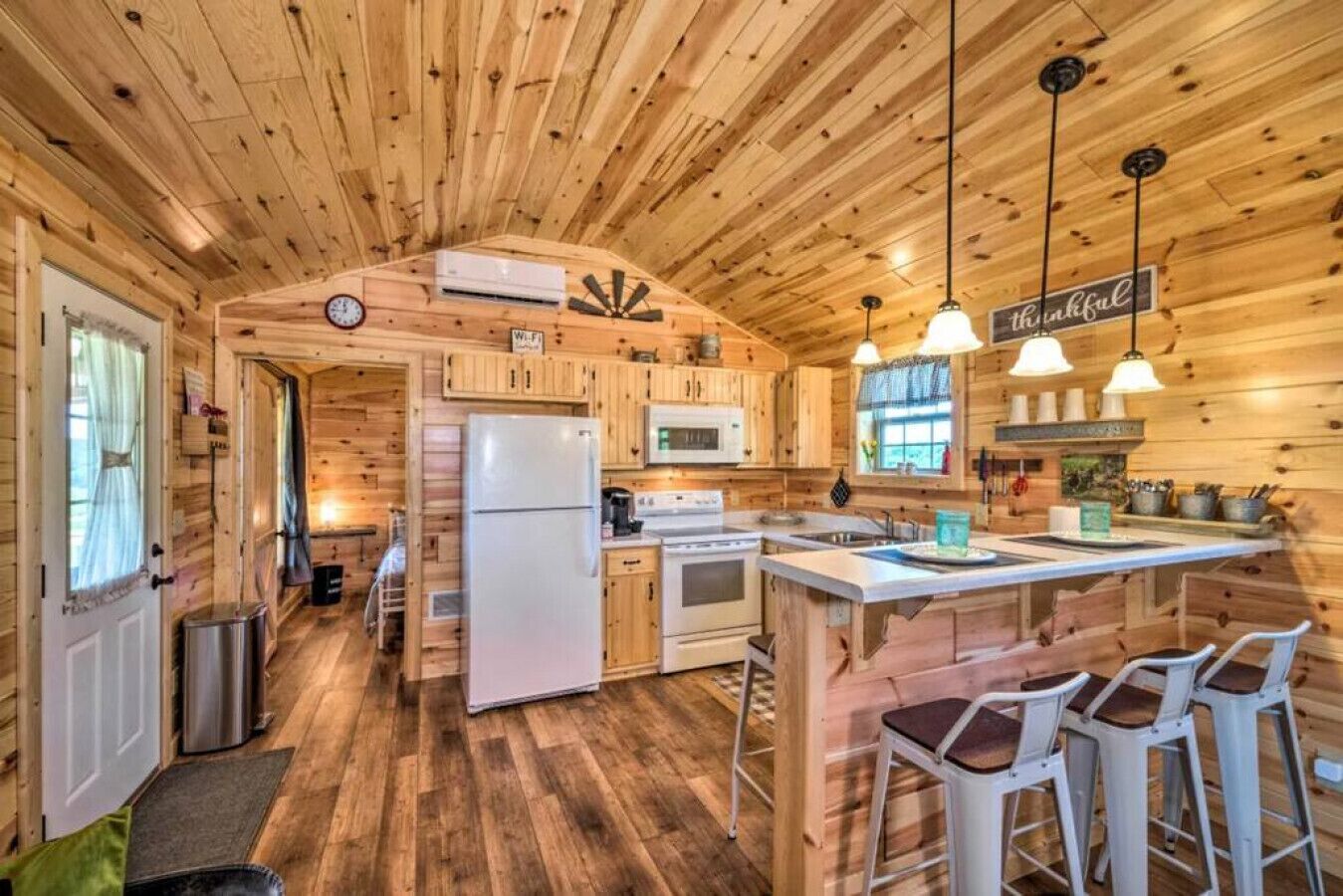 A wooden cabin interior with a kitchen, bar area, and a dining space.