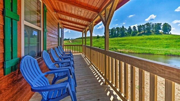 Eine überdachte Veranda mit blauen Stühlen und Blick auf ein grünes Feld und Fluss.