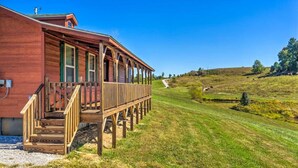 Ein hölzernes Gebäude mit einer Veranda und einer grünen Landschaft im Hintergrund.