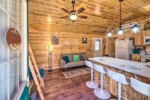 A wooden interior with a kitchenette, a sofa, a dining area with bar stools, a ceiling fan, and a sign indicating Wi-Fi availability. - Mammoth Cave Cabin Rentals 5 - 12.8 miles from Mammoth Cave National Park (Mammoth Cave)