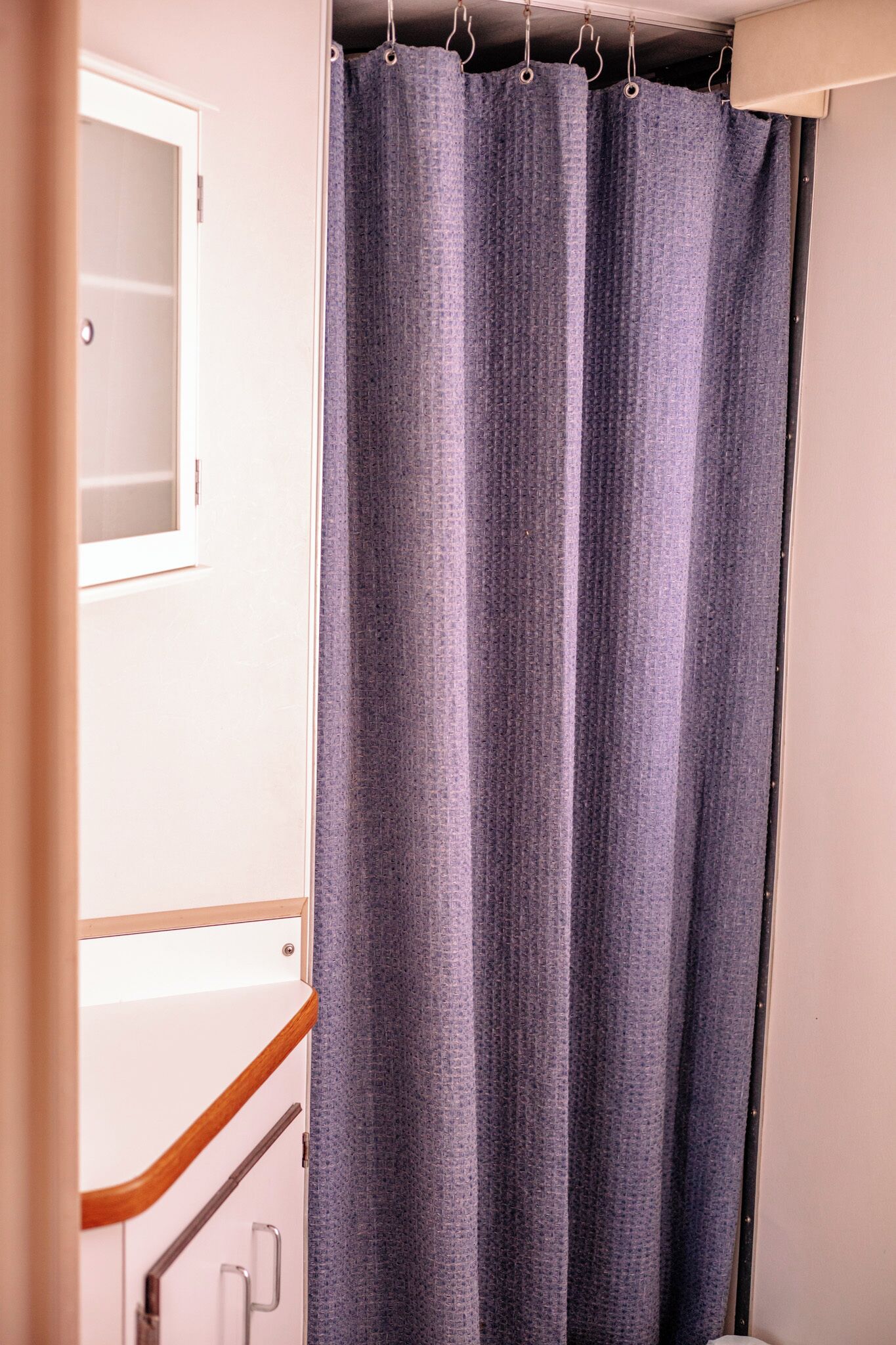 A bathroom with a shower curtain, a mirror, and a towel rack.
