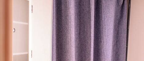 A bathroom with a shower curtain, a mirror, and a towel rack.