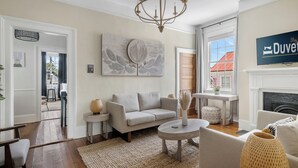 A spacious living room with a neutral color palette, featuring a sofa, a coffee table, and a fireplace.