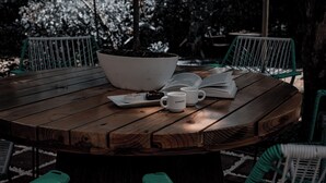 A round wooden table with a white bowl, a book, and two white coffee cups. - Condo Pacifico Quepos, 5 minutes from National Park Manuel Antonio (Quepos)