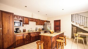 A modern kitchen with wooden cabinets, a granite countertop, and a central island with stools. - Condo Pacifico Quepos, 5 minutes from National Park Manuel Antonio (Quepos)