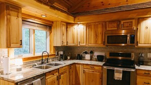 Cocina de madera con pileta, estufa, microondas y alacenas.