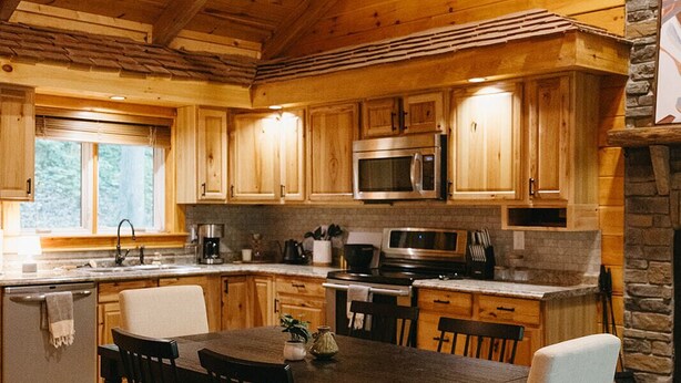 Una cocina rústica de madera con chimenea de piedra, armarios de madera y un comedor con mesa y sillas.