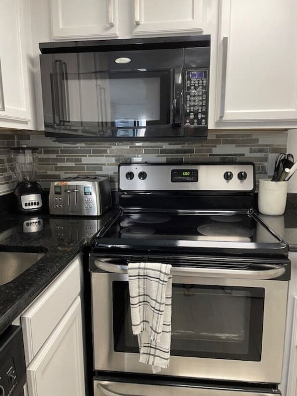 Enjoy cooking in this well-equipped kitchen with a microwave, toaster, and oven, along with ample cabinetry and a countertop.