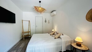 A bedroom with a bed, a hanging light fixture, a bedside table with a lamp, and a wardrobe.