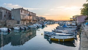 A marina with boats docked along a waterfront with buildings on one side.
