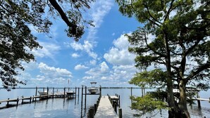A wooden dock extending into calm water, surrounded by trees and boats docked at the pier. - New Bern Waterfront Sunset (New Bern)