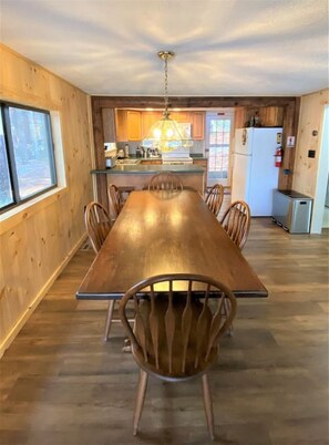 Enjoy meals in this cozy dining area with a long table and six chairs, surrounded by a warm and inviting interior design.