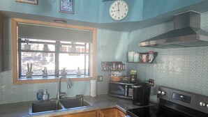 A kitchen with wooden cabinets, a stainless steel sink, a microwave, and a stove. - Cottage with a stone fire pit and pet friendly! (Flagstaff)